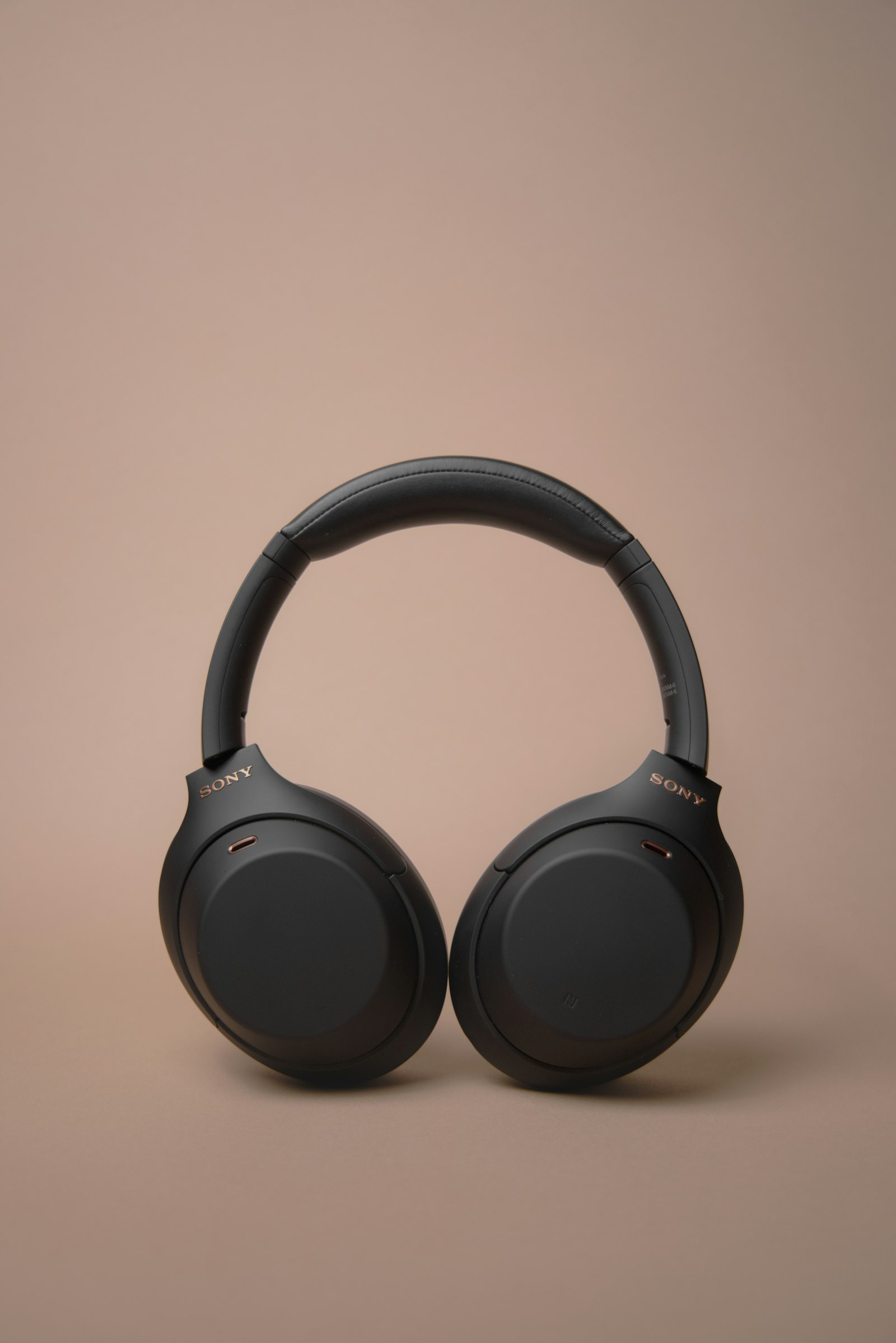 Black Sony over-ear headphones with a padded headband on a beige background.
